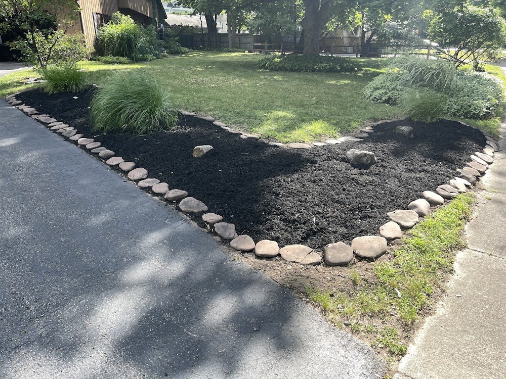 Fresh black mulch bed with a natural stone border